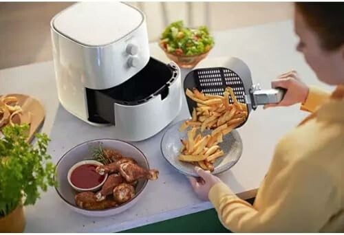 Person serving fries from an air fryer onto a plate