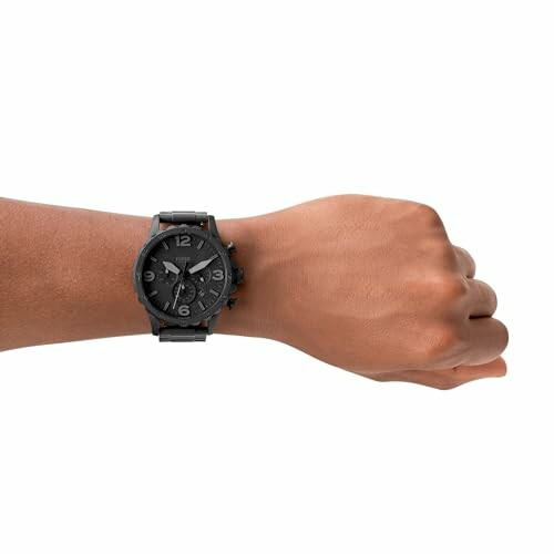 Hand wearing a black wristwatch with a dark dial.