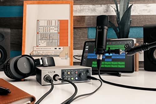 Home recording studio setup with audio interface, microphone, headphones, and tablet.