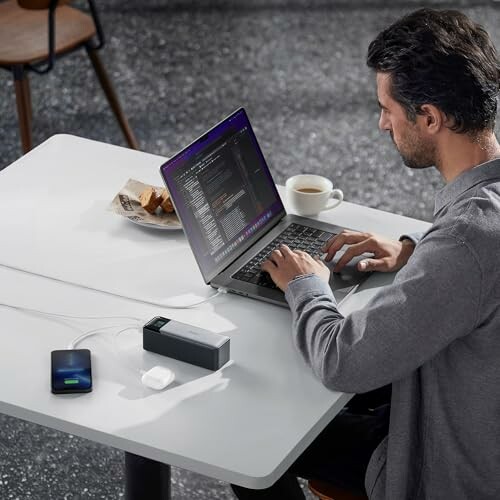 Man working on laptop with external devices connected on a table.