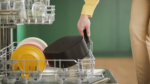 Person placing a pan in a dishwasher.