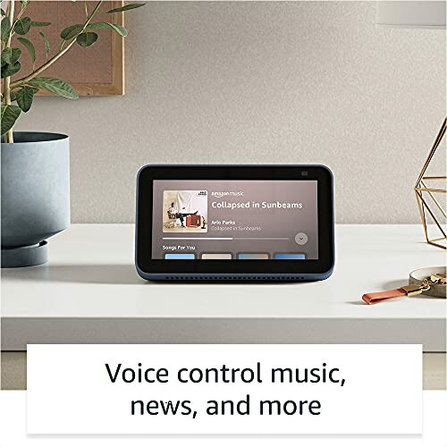 Smart speaker on a table with a screen displaying music options.