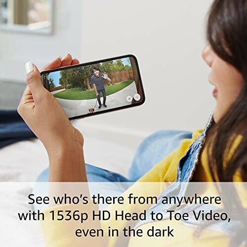 Person holding a smartphone displaying video of a man outside.