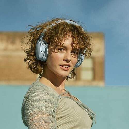 Woman with curly hair wearing blue headphones outdoors